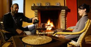 Un uomo che versa un bicchiere di vino davanti al camino di B&B Scacciapensieri - Vini d'Altura a Colledara