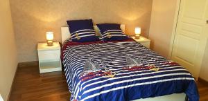 a bedroom with a large bed with blue and white stripes at t2 lumineux avec balcon in Saint Malo