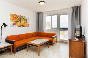 a living room with a couch and a tv at Apartamentos Palm Garden by LIVVO in Morro del Jable