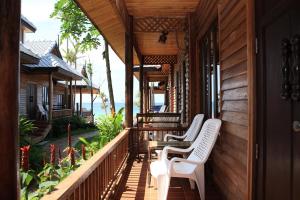 a porch of a house with white chairs on it at Baan Pakgasri Hideaway in Ko Lanta