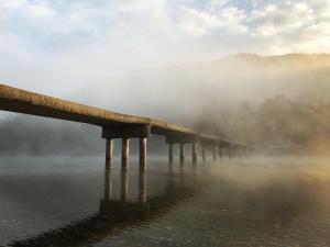 a bridge over a body of water in the fog at Shimanto Riverside Hideaway in Shimanto