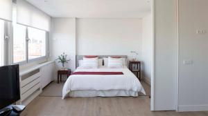 a white bedroom with a bed and a tv at Heima Colon Square Amazing Views in Madrid
