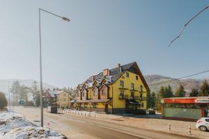 une maison jaune sur le côté d'une rue dans l'établissement Hotel Majerzanka, à Piwniczna-Zdrój