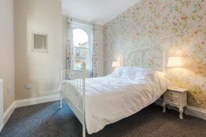 a bedroom with a white bed with floral wallpaper at The Smugglers Retreat in Hastings