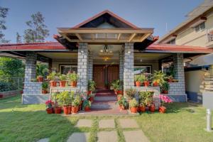 a house with potted plants on the front of it at Srinikethana Home Stay with Swimming Pool in Madikeri