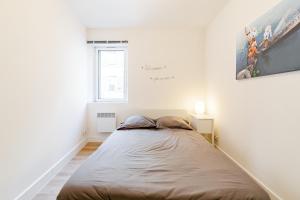 ein großes Bett in einem weißen Zimmer mit Fenster in der Unterkunft Maison de ville pour 4 personnes in Marseille