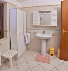 a white bathroom with a sink and a mirror at B&B Mitzixeddas in Màndas