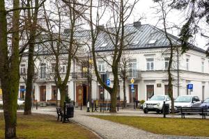 duży biały budynek z samochodami zaparkowanymi w parku w obiekcie Perla w mieście Augustów