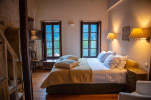 a bedroom with a bed and two windows at Epoches Luxury Suites in Karpenisi
