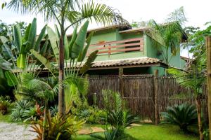a green house with a fence and palm trees at Casa Viva Itamambuca in Ubatuba
