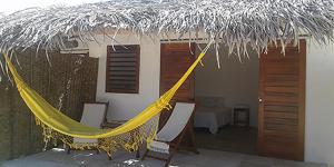 a hammock outside of a house with a straw roof at Pousada Villa Aloha in Patos +16 photos