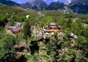 a house on a hill with mountains in the background at Thethi Paradise Hotel & Restaurant in Theth