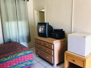 a tv sitting on top of a dresser in a bedroom at Sunset Inn- Fort Pierce, FL in Fort Pierce