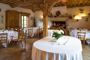 a room with white tables and chairs and a fireplace at Le Hameau de Barboron in Savigny-lès-Beaune