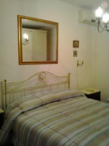 ピアッツァ・アルメリーナにあるLa Dea Bendataのベッドルーム1室(壁に鏡付きのベッド1台付)
