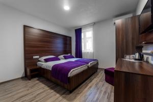 a bedroom with a large bed with purple sheets at Apartments and Rooms Villa Majestic in Bihać