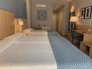 a hotel room with two beds and a desk at Hotel Puerta del Mar - Adults Recommended in Nerja