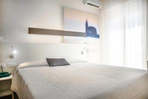 een witte slaapkamer met een groot bed en een raam bij Hotel Antoniana in Caorle