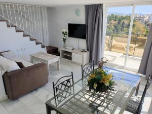 a living room with a glass table and a television at Skol 617 Beachfront Two-bedrooms Duplex With Sea Views in Marbella