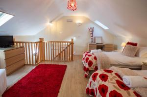 a attic bedroom with two beds and a red rug at Mollett's Farm in Saxmundham
