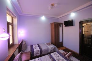 Habitación con 2 camas y TV en la pared. en Alliance hotel bukhara, en Bukhara