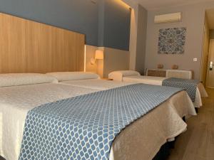 a hotel room with two beds with blue and white sheets at Hotel Puerta del Mar - Adults Recommended in Nerja
