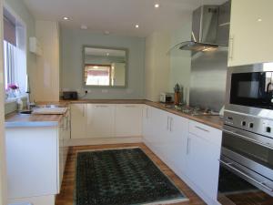 a kitchen with white cabinets and a kitchen rug at Lindfields in Inverness