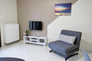 a living room with a chair and a tv at San Giorgio Luxury Apartments in Ierissos