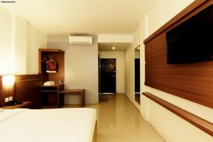 a bedroom with a bed and a flat screen tv at Alzara Hotel Syariah in Wonosari