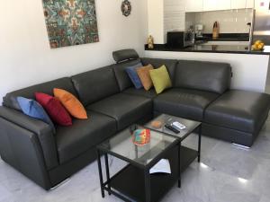 un sofá de cuero negro con almohadas coloridas y una mesa en Avda de las Palmeras Apartment en Benalmádena