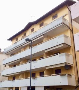 un edificio de apartamentos con balcones blancos y luz de la calle en Al Parco delle Rose, en Grado