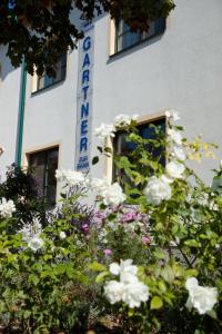 Pension Gartner في Wallern im Burgenland: علامة على جانب المبنى مع الزهور البيضاء