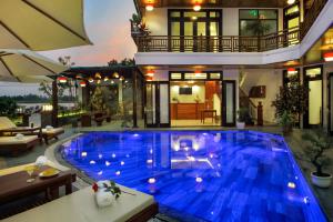 a house with a large blue pool in front of a house at Threeway Riverside Villa in Hoi An