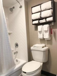 a bathroom with a toilet and a shower with towels at Ramada by Wyndham Suites Orlando Airport in Orlando