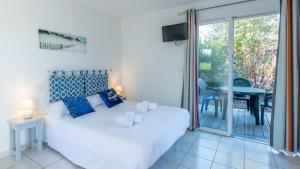 ein Schlafzimmer mit einem weißen Bett und einer Glasschiebetür in der Unterkunft Vacancéole - Le Domaine des Grands Lacs in Parentis-en-Born