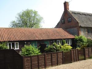 a house with a wooden fence in front of it at Thorpegate Cottage in Thorpe Market