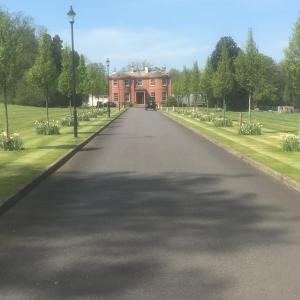 a long road leading to a large red brick house at Woodland House Hotel in Dumfries