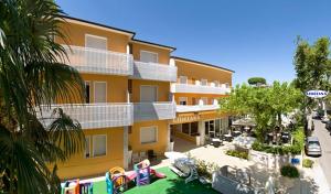 un grand bâtiment jaune avec des bateaux dans un port de plaisance dans l'établissement Hotel Giuliana, à Cervia