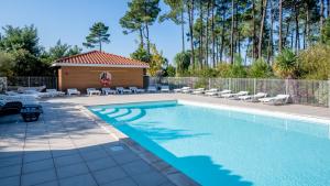 einen Pool mit Stühlen und ein Gebäude in der Unterkunft Vacancéole - Le Domaine des Grands Lacs in Parentis-en-Born