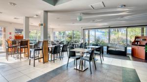 ein Restaurant mit Tischen und Stühlen und Fenstern in der Unterkunft Vacancéole - Le Domaine des Grands Lacs in Parentis-en-Born