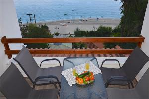 a table with a bowl of vegetables on a balcony with a beach at Appartments Zoe in Agios Ioannis Pelio
