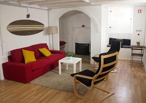 a living room with a red couch and two chairs at Watermark Surf House in Espinho