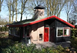 エルメロにあるPark De Haeghehorstの煙突と赤い扉のある小さな家