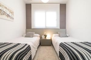 two twin beds in a room with a window at Sunset Drive Benidorm by Mar Holidays in Benidorm
