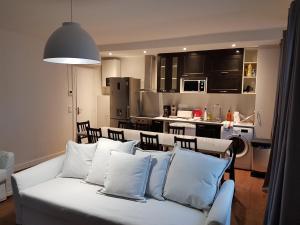 a living room with a white couch and a kitchen at Meublés de Tourisme à Vincennes in Vincennes