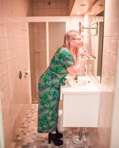 a woman standing in a bathroom brushing her teeth at Kesähotelli Aurora in Tampere