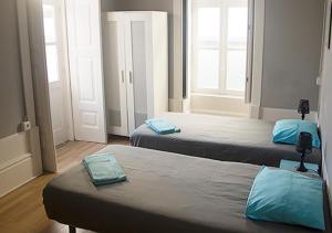 two beds with blue pillows in a room at Watermark Surf House in Espinho
