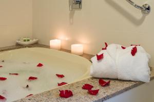 uma casa de banho com rosas vermelhas num lavatório com velas em Vila Suzana Parque Hotel em Canela