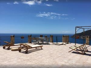 a patio with a table and benches and the ocean at Appartamento a Moneglia, tra Portofino e le Cinque Terre in Moneglia