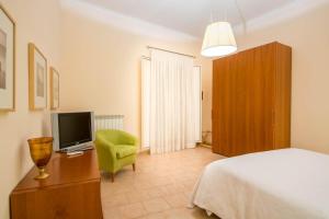 Schlafzimmer mit einem Bett, einem TV und einem Stuhl in der Unterkunft La Residenza in Neapel
